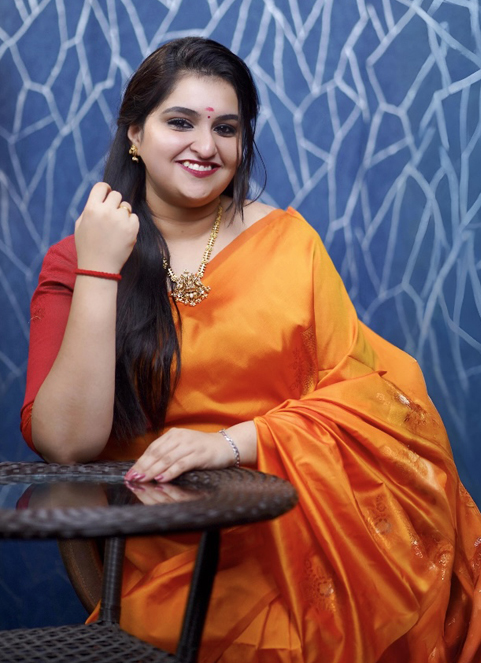 Woman in teal Kanchipuram saree holding lotus flower